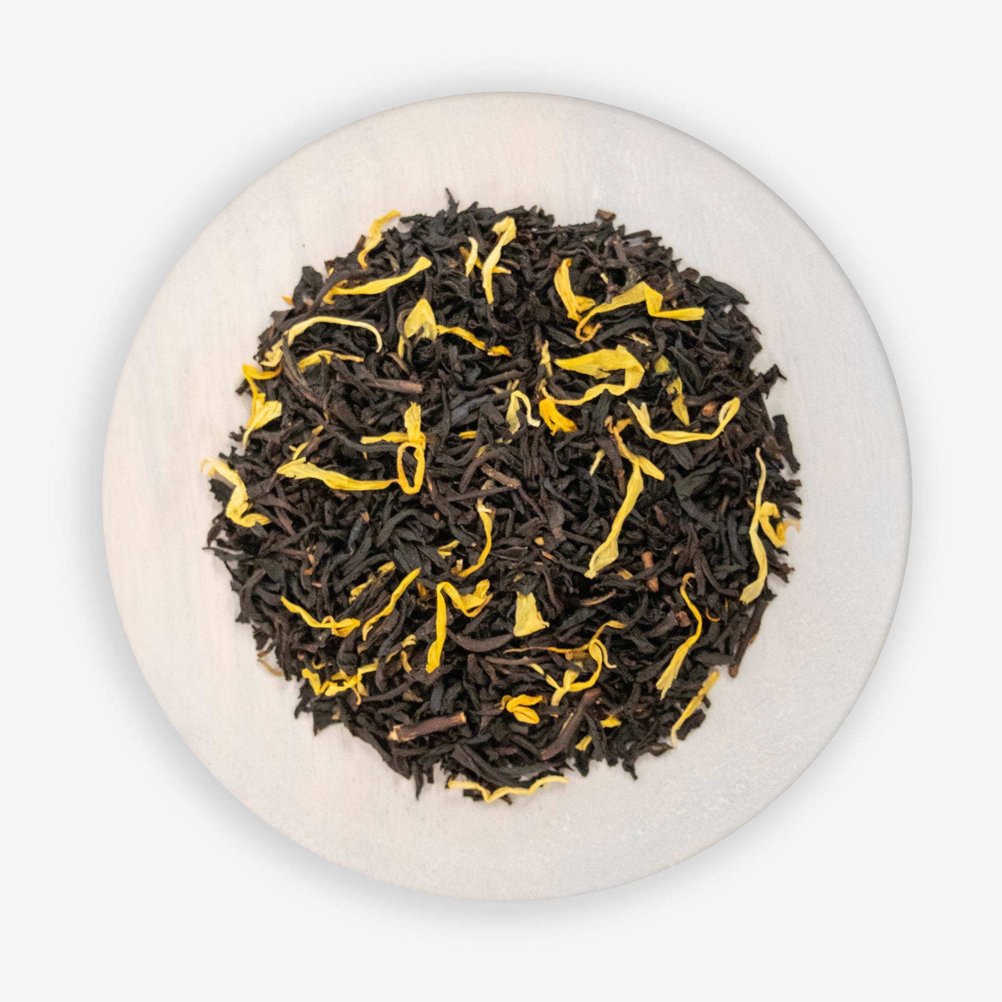A top-down image of a plate containing dried black tea leaves and apricot pieces, indicative of the Apricot Black Tea product.