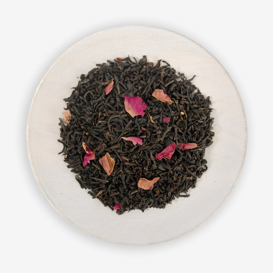 A dish containing black tea leaves with pieces of rose petals scattered throughout.