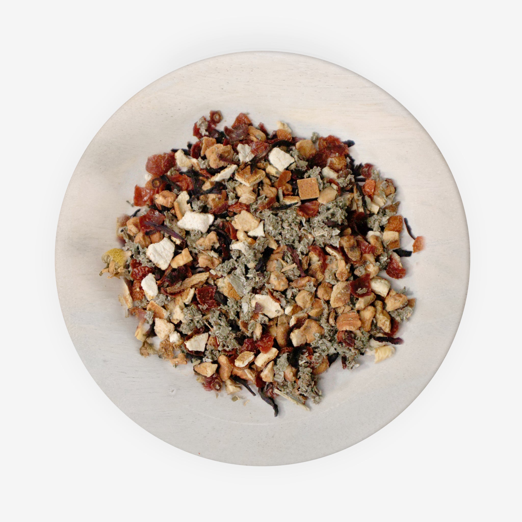 A mixture of dried fruits and herbs on a plate, likely to be used as ingredients for Pomberry Punch tea.