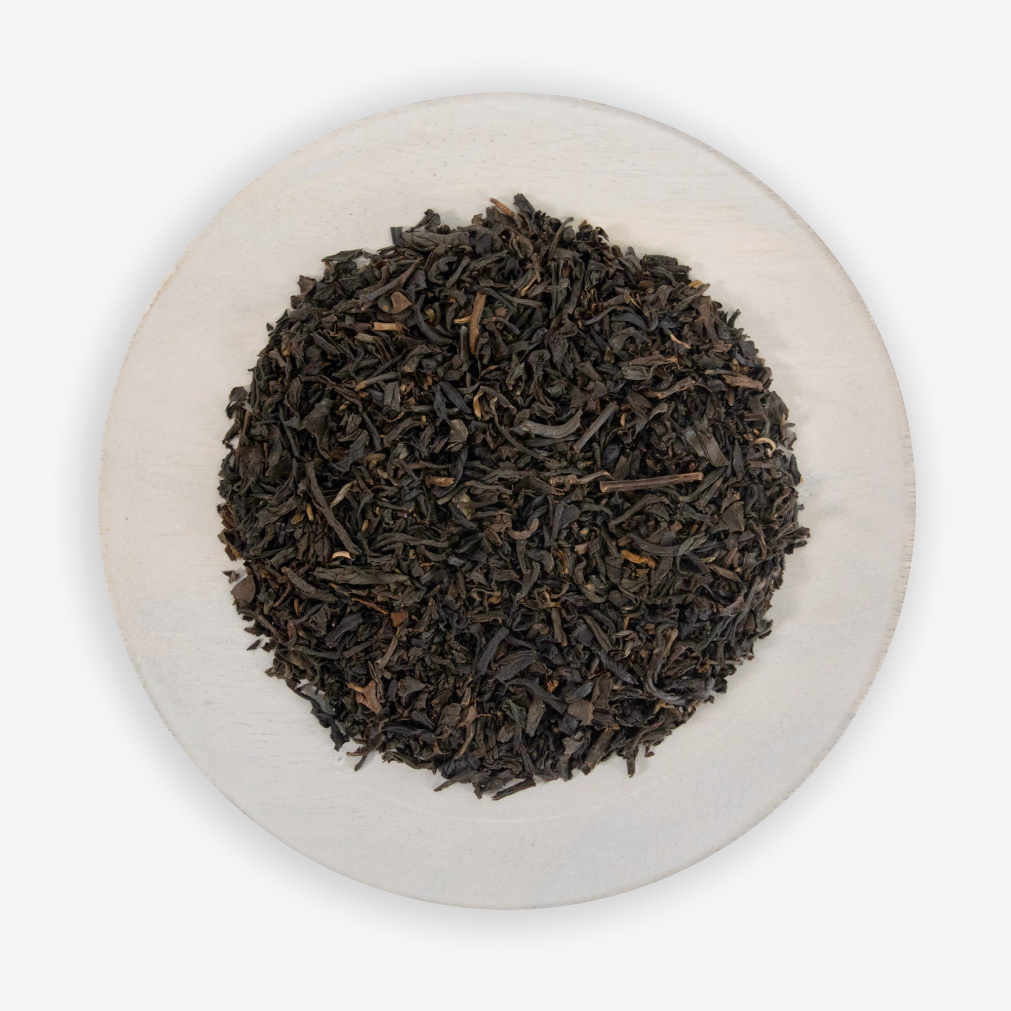 A plate of fine black tea leaves mixed with pieces of all-natural vanilla flavor.