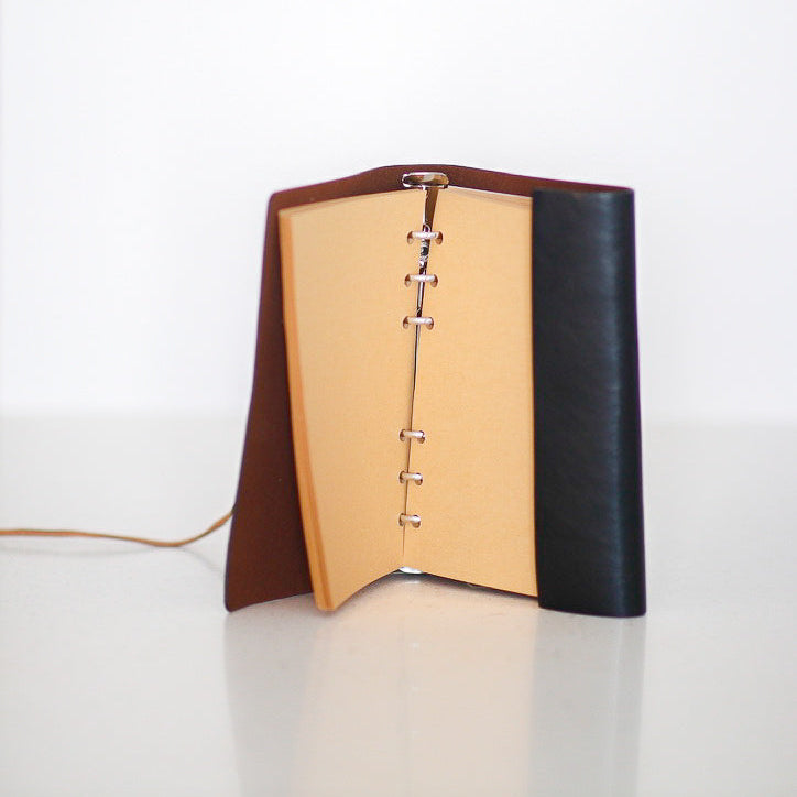 Two-tone leather notebook with brown and black cover on a white background
