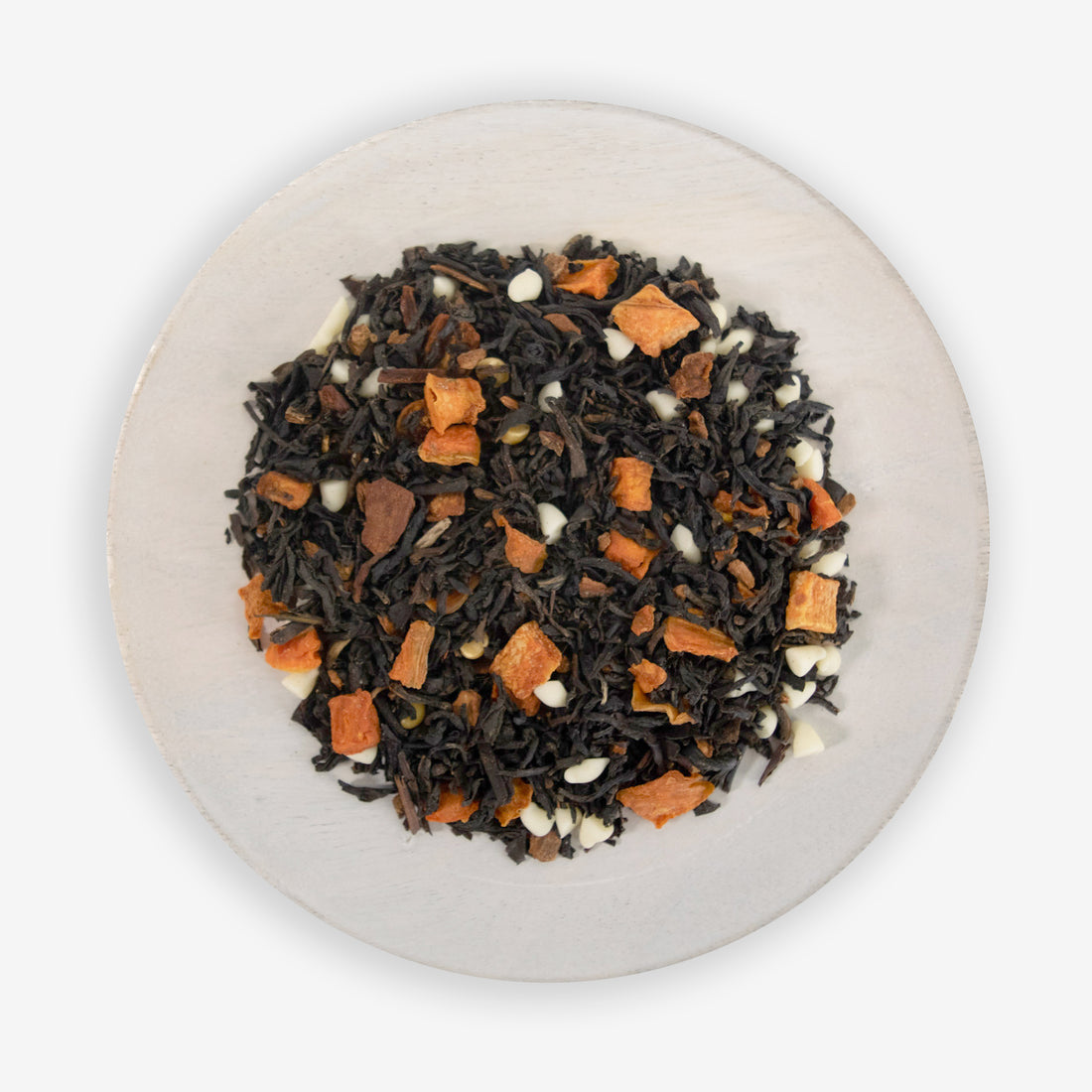 A plate with pumpkin muffin tea leaves, which include black tea, white chocolate chips, and freeze-dried carrot pieces.